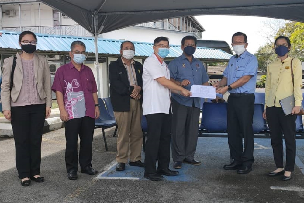 Dr Wong (front, left) handing over the Miri Field Hospitalu00e2u20acu2122s plan to Lee while Ik Pahon (centre) and others look on. u00e2u20acu2022 Borneo Post pic