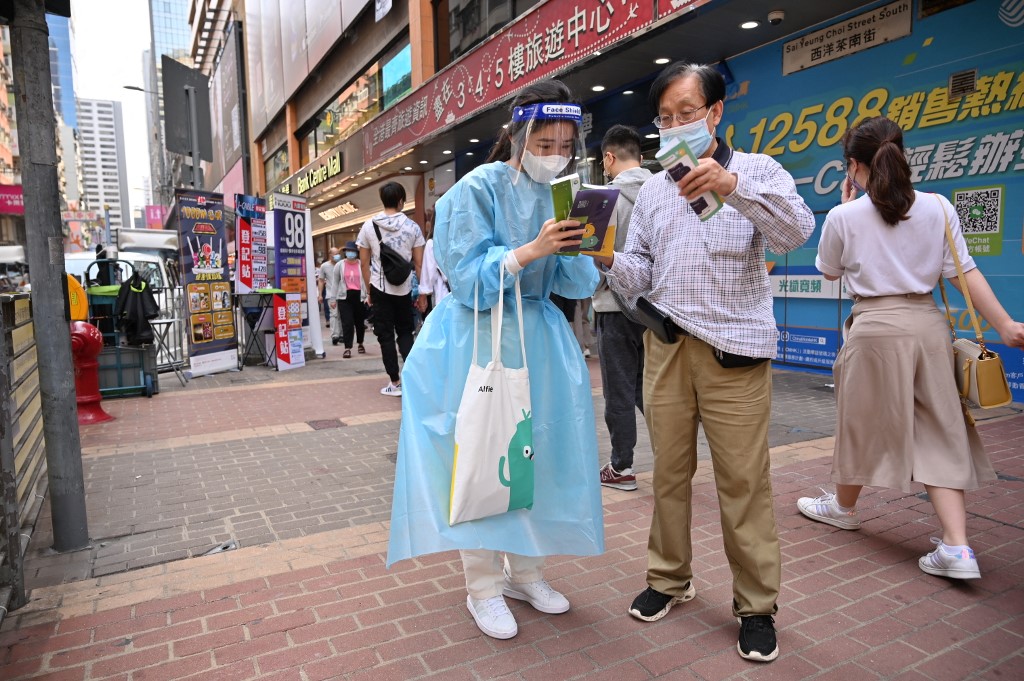 A woman wearing PPE promotes Covid-19 testing kits in the Mongkok area of Hong Kong on March 19, 2022. u00e2u20acu201d AFP pic