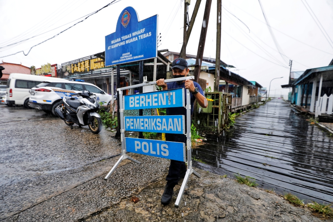 A policeman takes a police sign back to a police vehicle at the Muara Tebas Wharf. u00e2u20acu201d Borneo Post pic