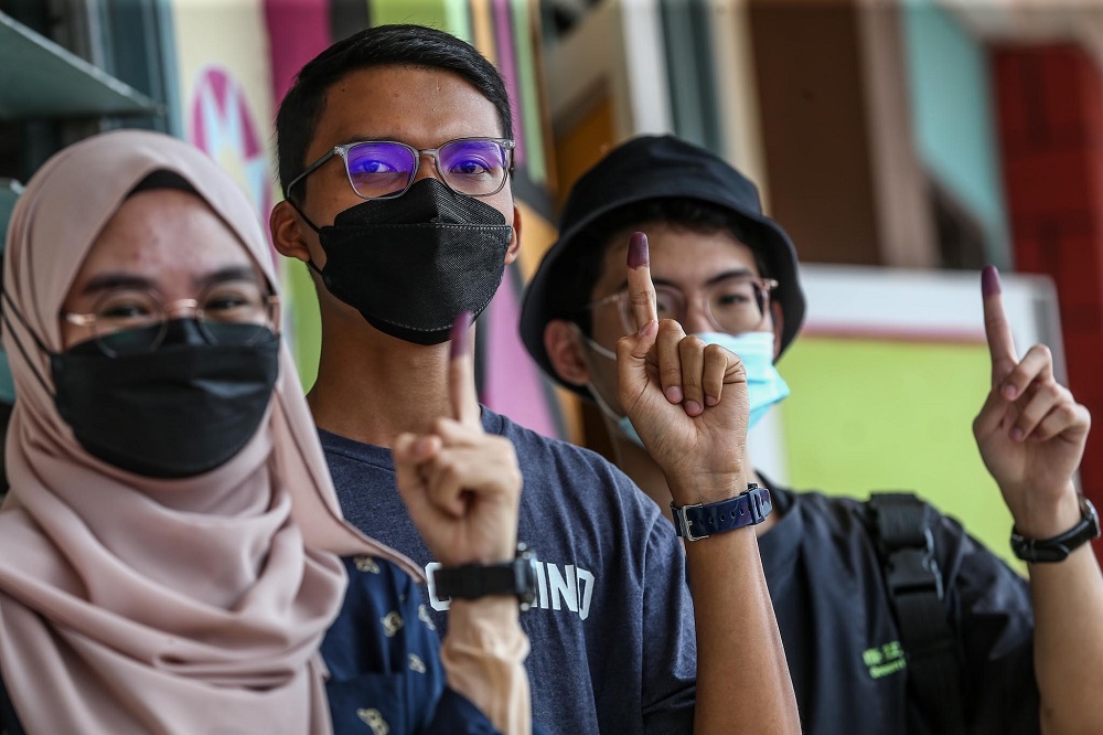 First-time voters Syazwani Rafaeh Shukor, 19 (left), Mohd Khairul Azhar Mohd Ridza, 18, (centre) and Jonathan Chua Ming Jun, 19 (right) at the SK Ismail 1 polling centre to cast their votes, March 12, 2022. u00e2u20acu2022 Picture by Hari Anggara