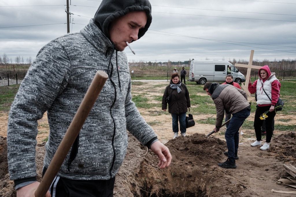 Oleksandr Smagliuk (left), helps to bury the coffin of his relative Mykhailo Romaniuk, who was shot dead while riding bicycles together on Yablunska Street in Bucha on March 6, 2022, during the Russian occupation, at a cemetery in Bucha, April 19, 2022. u00e2