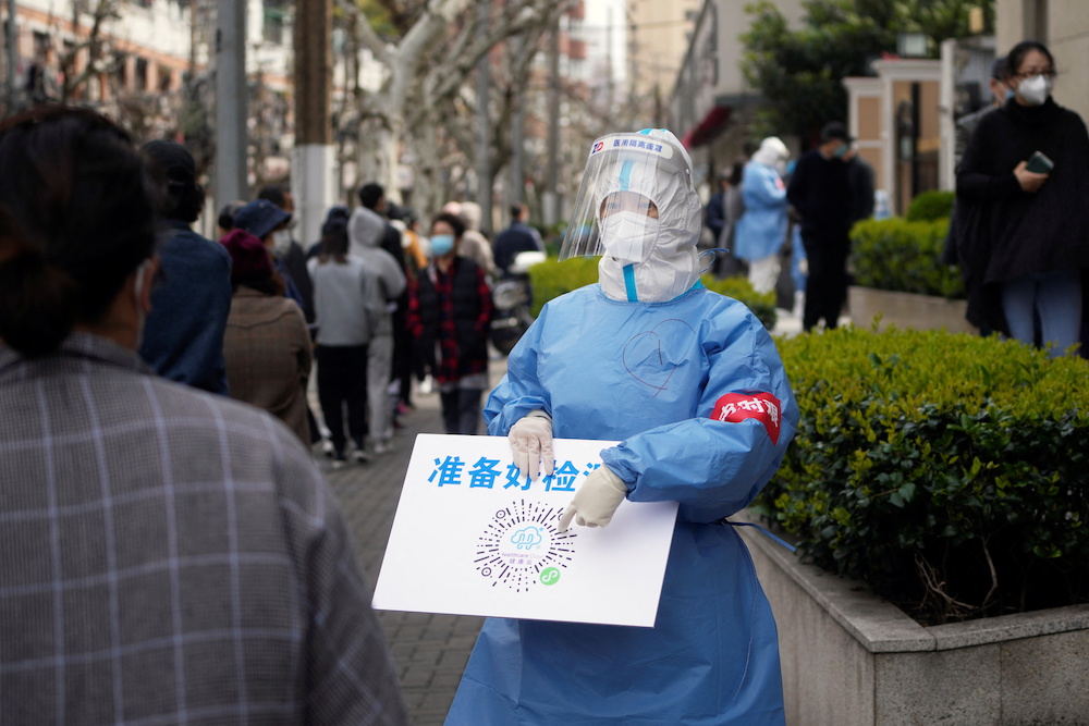 A worker in a protective suit shows a QR code to residents lining up for nucleic acid testing, as the second stage of a two-stage lockdown to curb the spread of Covid-19 begins in Shanghai, China April 1, 2022. u00e2u20acu201d Reuters pic