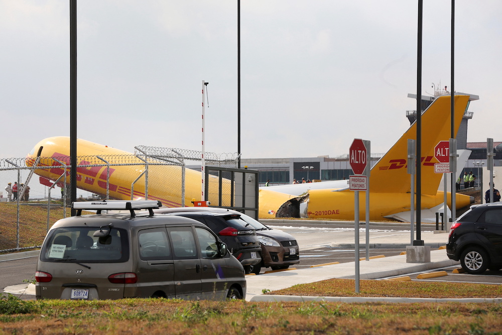 Airport personnel stand at the scene where a Boeing 757-200 cargo aircraft operated by DHL made an emergency landing before skidding off the runway and splitting, Juan Santamaria International Airport in Alajuela, Costa Rica April 7, 2022. u00e2u20acu201d Reuters pic