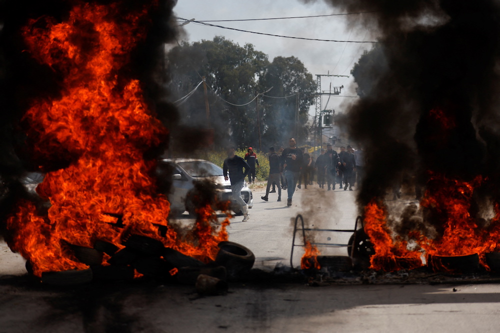 Palestinians run near burning tires during clashes with Israeli forces following a raid, in Jenin in the Israeli-occupied West Bank April 9, 2022. u00e2u20acu201d Reuters pic