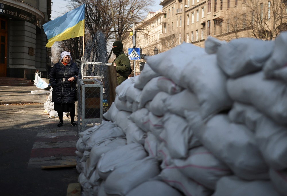 A woman interacts with a Ukrainian serviceman at a checkpoint, as Russia’s invasion of Ukraine continues, in Odesa, Ukraine March 30, 2022. — Reuters pic