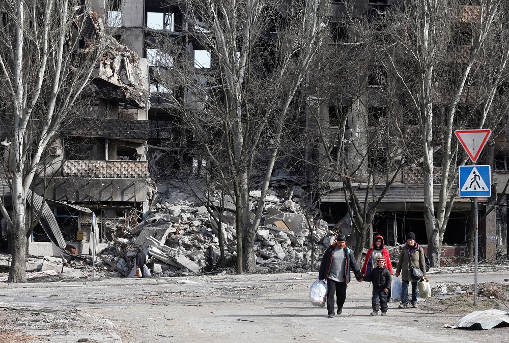 Local residents walk past an apartment building destroyed during Ukraine-Russia conflict in the besieged southern port city of Mariupol, Ukraine March 31, 2022. REUTERS/Alexander Ermochenko