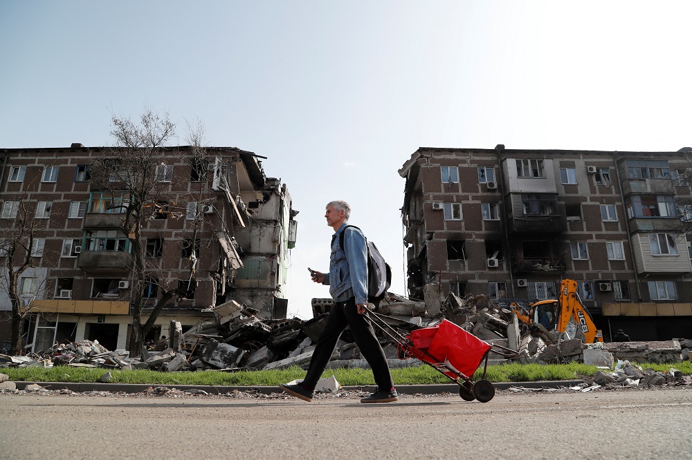 A local resident walks past an apartment building damaged during Ukraine-Russia conflict in the southern port city of Mariupol, Ukraine April 19, 2022. — Reuters pic