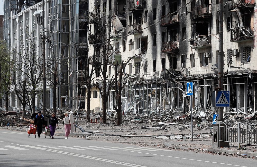 People walk along a street near a building damaged during Ukraine-Russia conflict in the southern port city of Mariupol, Ukraine April 25, 2022. u00e2u20acu201d Reuters pic