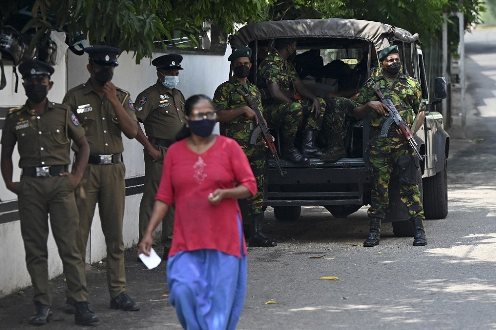 A pedestrian walks past Special Task Force and police personnel standing on guard along a street in Colombo April 2, 2022. u00e2u20acu201d AFP pic