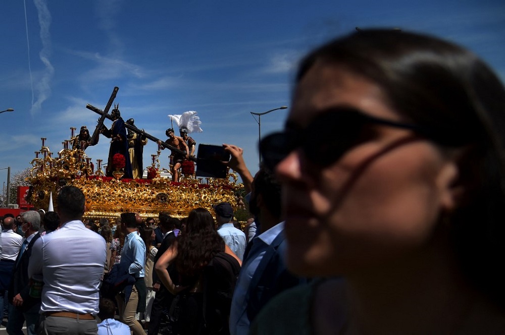 People watch a float with a statue of ‘Jesus de la Victoria’ (Christ of victory) during the Holy Week’s Palm Sunday procession in Seville April 10, 2022. — AFP pic