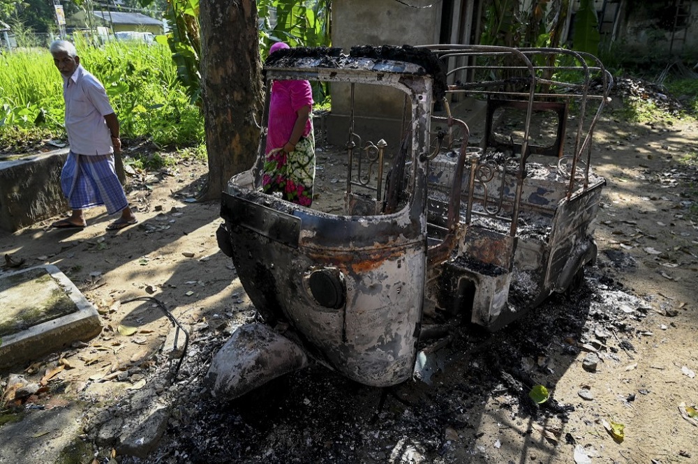 People walk past a burnt three-wheeler in Rambukkana April 20, 2022. u00e2u20acu201d AFP pic