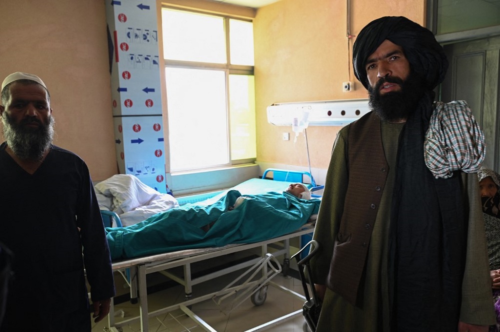 A Taliban fighter (right) stands next to a wounded youth receiving treatment at a hospital in Kabul April 19, 2022. u00e2u20acu201d AFP pic