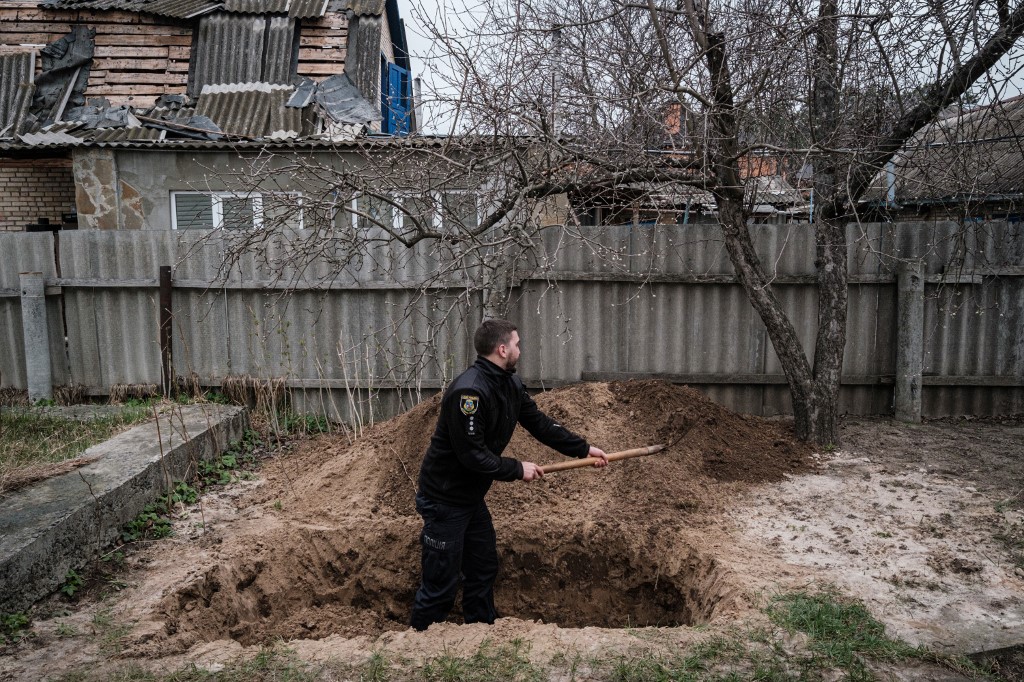 Police officer Bogdan Demtsiura exhumes the body of Andriy Samforskyi, who died at the age of 87 from a disease on March 26, as he was temporarily buried at his home in Bucha, on April 19, 2022, during the Russian invasion of Ukraine. u00e2u20acu201d AFP picn n