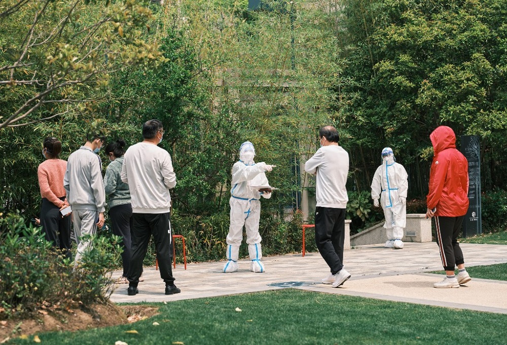 A community volunteer (centre) wearing personal protective equipment gestures as residents line up during a test for the Covid-19 coronavirus in a compound during a Covid-19 lockdown in Pudong district in Shanghai on April 19, 2022. u00e2u20acu201d AFP pic