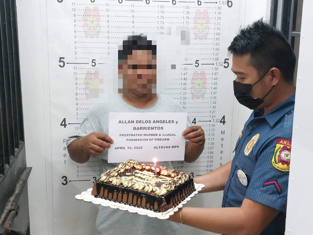 Policeman from the Altavas Municipal Police Station holding up a cake for Allan Barrientos Delos Angeles, who was arrested on the day of his 44th birthday. u00e2u20acu201d Picture via Facebook/ Altavas Municipal Police Station