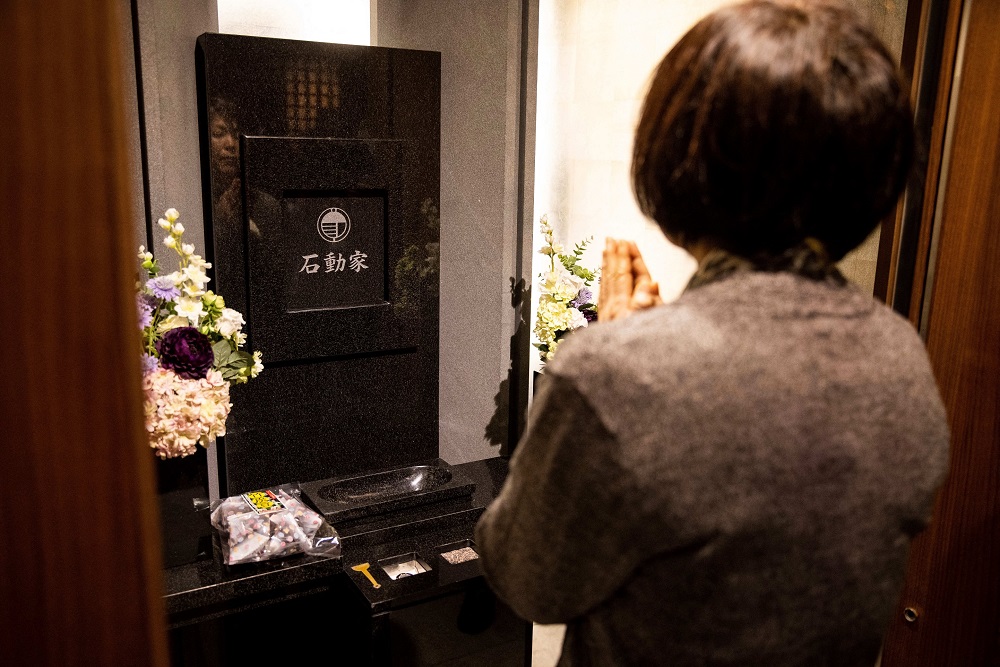 Masayo Isurugi prays in front of an altar with the urn containing her late husbandu00e2u20acu2122s ashes after an automated system delivered the zushi box to the mourning booth at the Kuramae-ryoen facility. u00e2u20acu201d AFP pic
