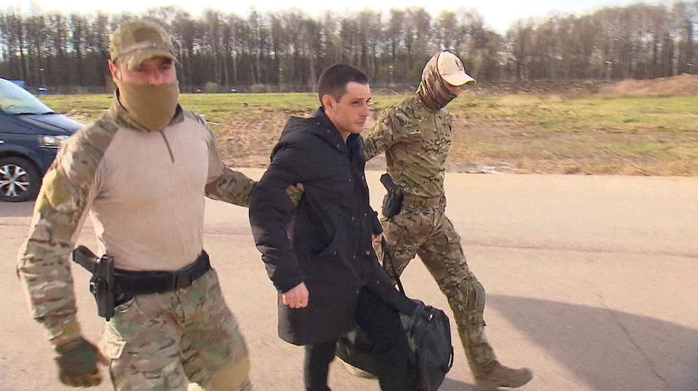 Former US Marine Trevor Reed is escorted to a plane by Russian service members as part of a prisoner swap between the US and Russia, in Moscow in this still image taken from video, April 27, 2022. u00e2u20acu201d RU24 handout via Reuters