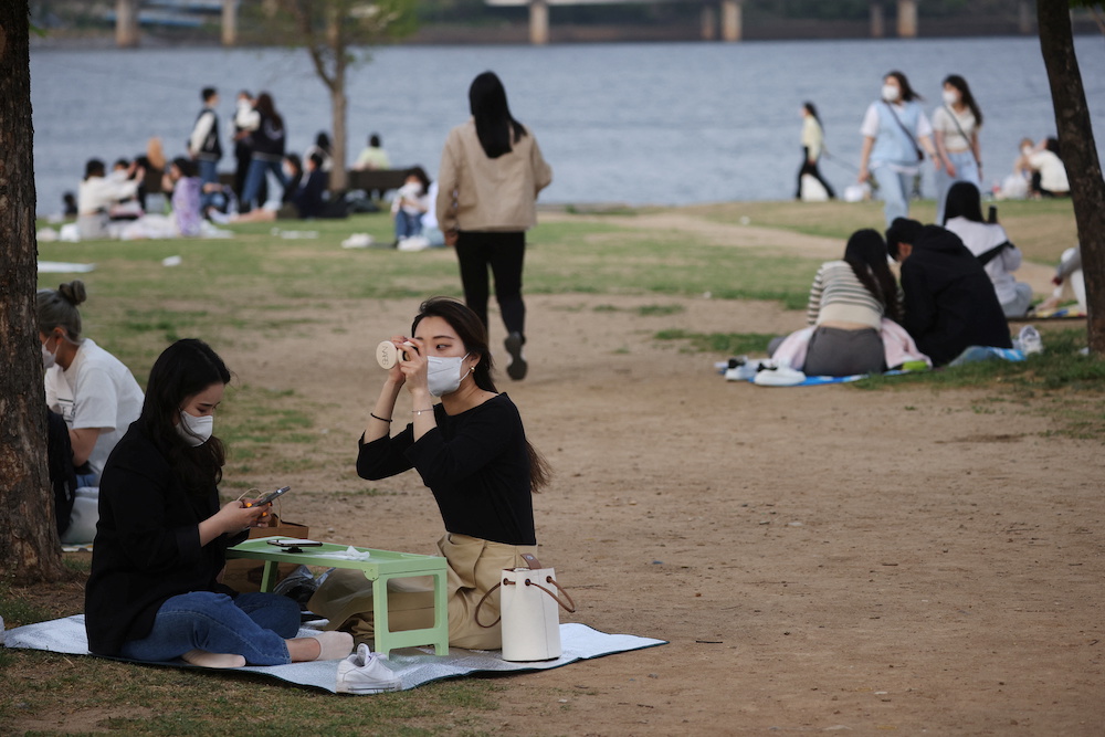 A woman wearing a mask, amid the Covid-19 pandemic, adjusts her makeup at a Han river park in Seoul, South Korea April 26, 2022. u00e2u20acu201d Reuters pic