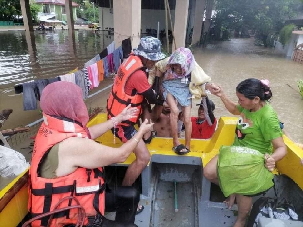 A rescuer assists an elderly woman onto a rescue boat, after the tropical storm Megi hit, in Capiz, Philippines April 12, 2022. u00e2u20acu2022 Philippine Coast Guard/Handout via Reuters