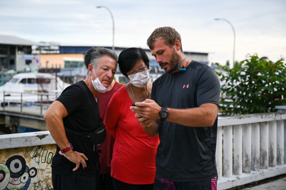 Alexandre Molina (left) and Esther Molina (centre), parents of missing Alexia Alexandra Molina from France, look at a phone during ongoing search efforts to locate three divers who went missing off Mersing April 8, 2022. u00e2u20acu201d AFP pic