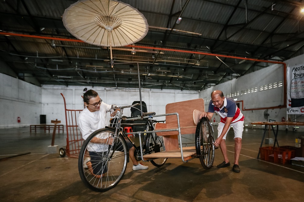 Diong (right) teaches Lim the technique of bending steel, a vital process in beca-making.