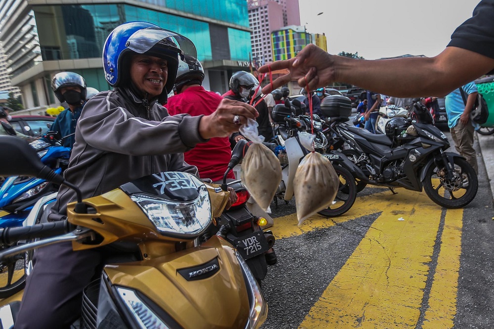 A motorist happily accepts his pack of ‘bubur lambuk’. ― Picture by Hari Anggara