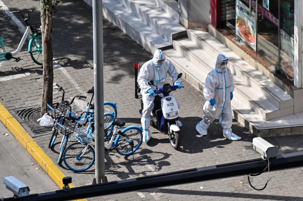 Officers, wearing personal protective equipment (PPE), walk next to the entrance of a neighbourhood during a Covid-19 lockdown in the Jingu00e2u20acu2122an district in Shanghai on April 8, 2022. u00e2u20acu201d AFP picnn