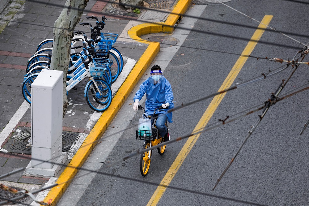 A woman in personal protective equipment (PPE) rides a bicycle on a street, during the lockdown to curb the spread of Covid-19 in Shanghai, China April 5, 2022. u00e2u20acu2022 Reuters pic