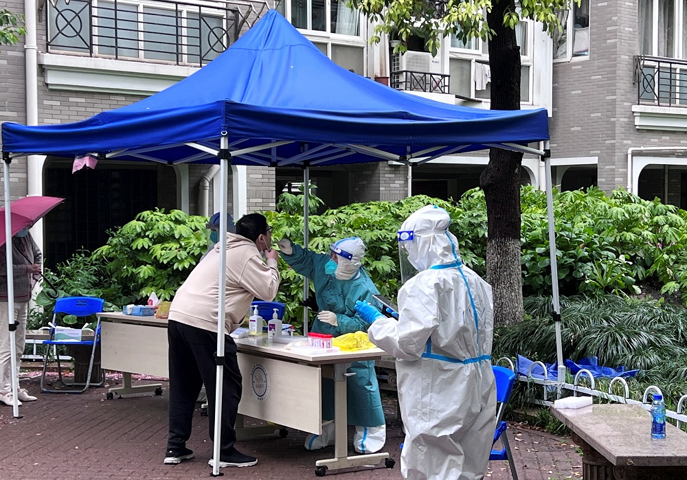 A medical worker in a protective suit collects a swab from a resident at a makeshift nucleic acid testing site inside a residential compound under lockdown in Shanghai, China April 14, 2022. u00e2u20acu2022 Reuters pic