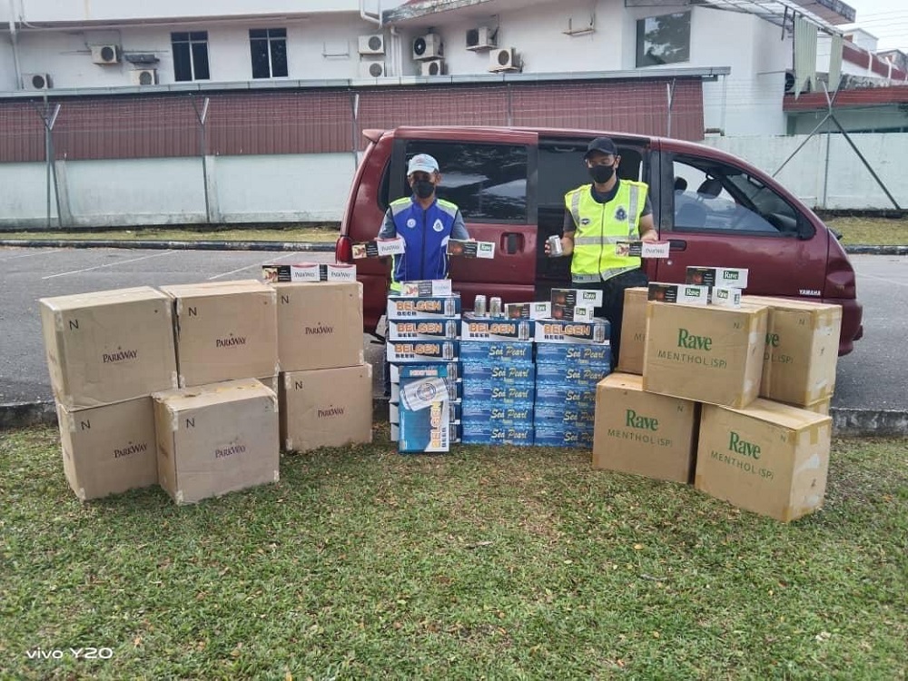 Officers show the seized cigarettes, alcoholic beverages and van. u00e2u20acu201d Borneo Post Online pic