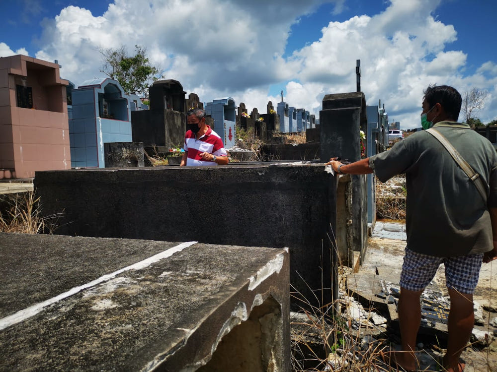 Sibu United Chinese Graveyard Association chairman Teo Boon Siew (left) checking on one of the affected graves. u00e2u20acu201d Picture by Anna Siaw Geok It/Borneo Post