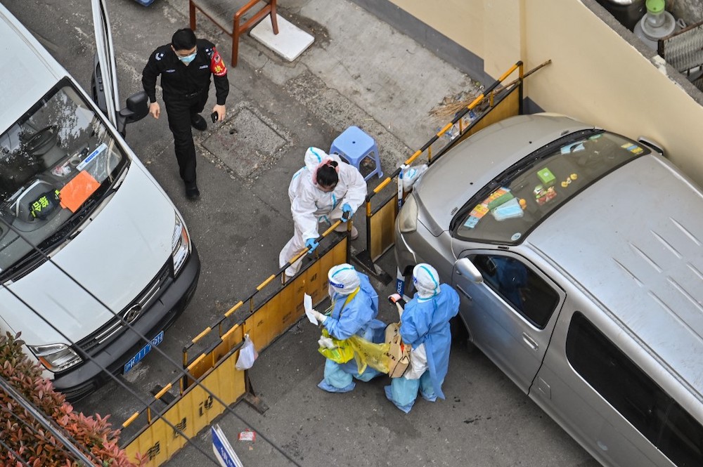 Health workers, wearing personal protective equipment, stand at a check point next to a neighborhood during a Covid-19 lockdown in the Jing'an district in Shanghai on April 8, 2022. u00e2u20acu201d AFP picnn