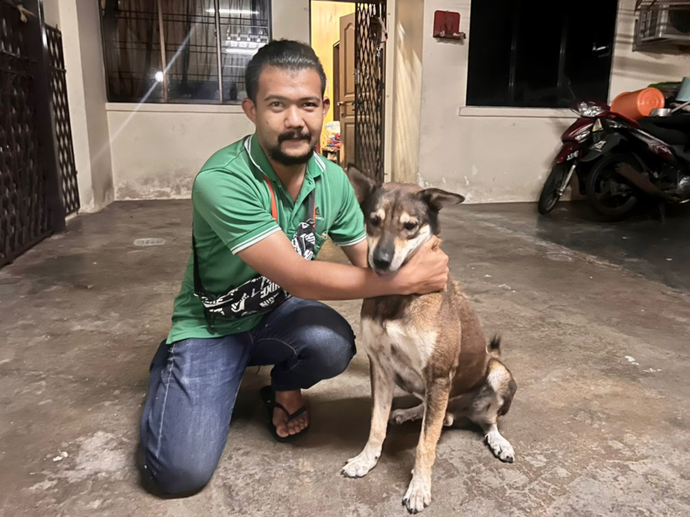 Singapore-based air-con technician Wee Liang Kuang with his pet dog On at their house on Jalan Simbang 1 in Taman Perling, Johor Baru, April 13, 2022. u00e2u20acu201d Picture by Ben Tannn