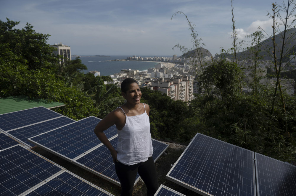 Owner of the hostel Eco Pousada Estrelas da Babilonia, poses on its roof covered by solar panels and overlooking Copacabana beach, at the Babilonia favela. u00e2u20acu201d AFP pic