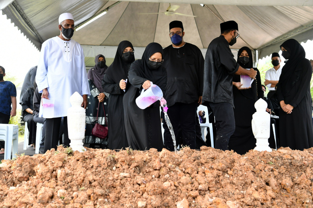 Puan Sri Rohani Abdullah, wife of the late Tan Sri Ali Hamsa, pours rose water on his grave at the Precinct 20 Muslim Cemetery in Putrajaya, April 25, 2022. u00e2u20acu201d Bernama pic 
