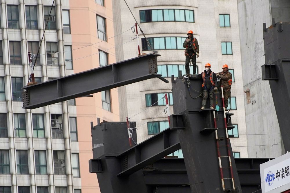 Workers watch as a crane lifts a structure at a construction site in Shanghai January 14, 2022. u00e2u20acu201d Reuters pic