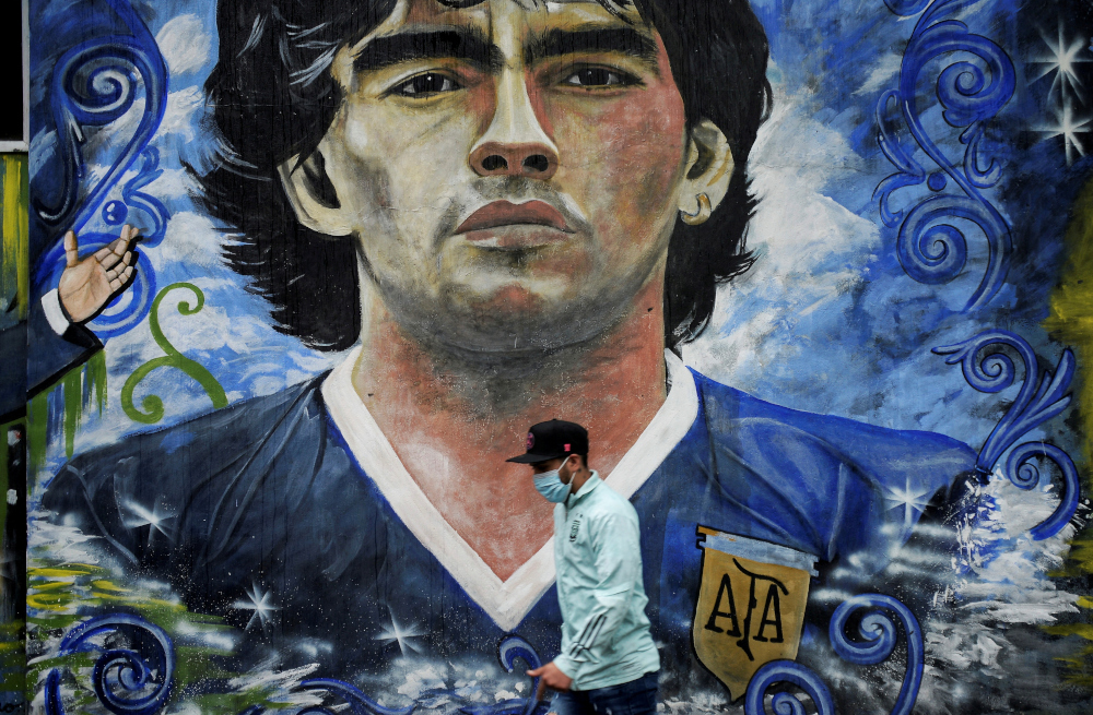 A pedestrian walks past a mural depicting late soccer legend Diego Armando Maradona in La Boca, on the first anniversary of his death, Buenos Aires, Argentina November 25, 2021. u00e2u20acu201d Reuters picnn