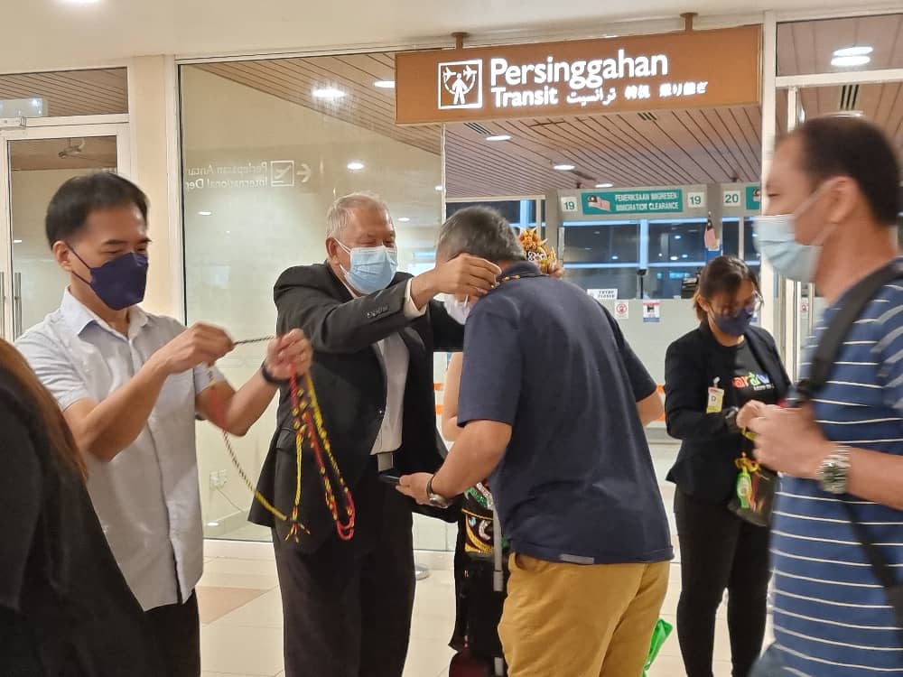 (From left) Hii and Ting welcoming the arriving passengers at the arrival gate. — Borneo Post Online pic