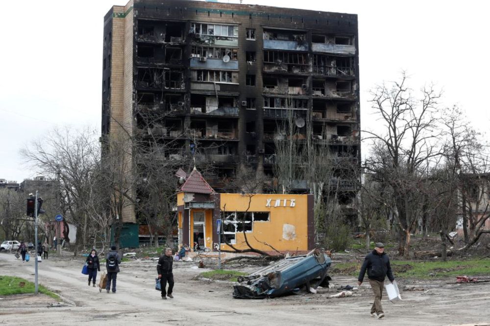 People walk past a residential building heavily damaged during Ukraine-Russia conflict in the southern port city of Mariupol, Ukraine April 21, 2022. u00e2u20acu201d Reuters pic