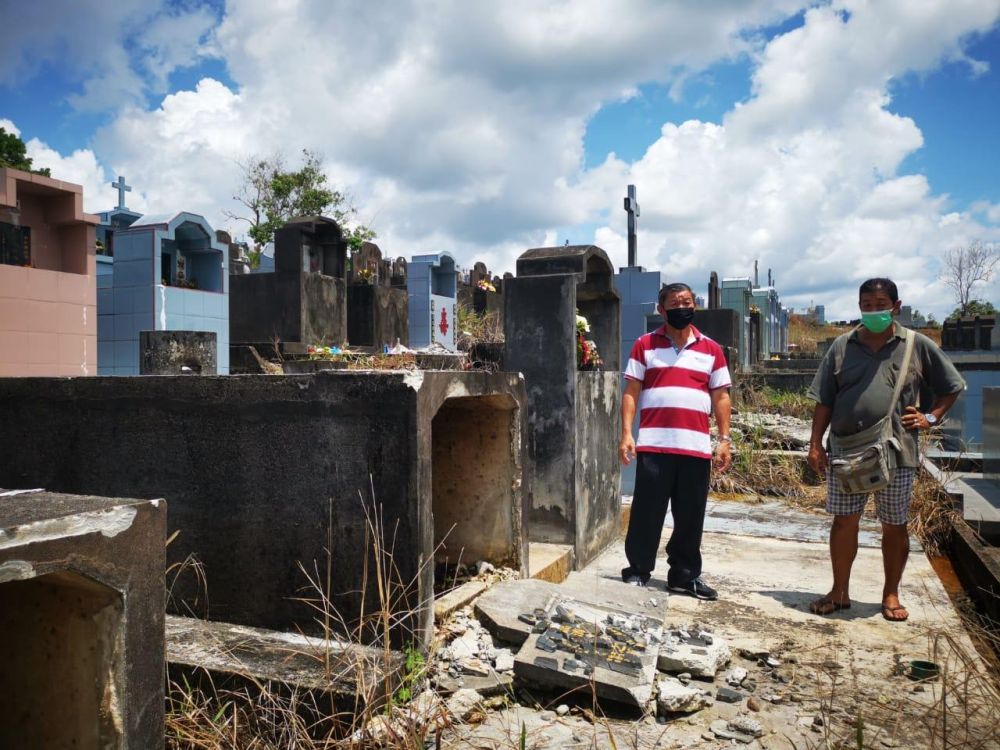 Teo (left) inspects one of the desecrated tombs. u00e2u20acu201d Borneo Post pic