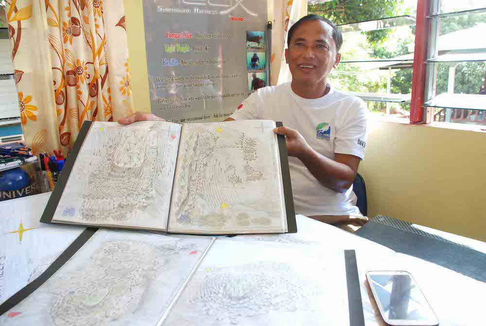 Glen showing some of his underwater mapping sketches. — Borneo Post pic