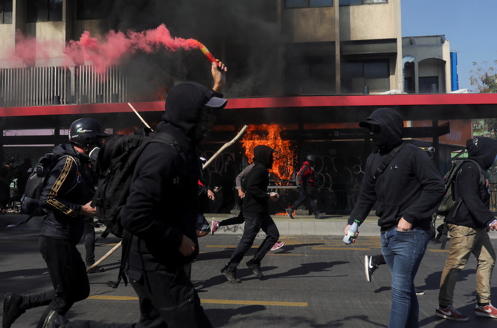 Fire burns at a bus stop as demonstrators run during the May Day rally in Santiago, Chile May 1, 2022. u00e2u20acu201d Reuters pic