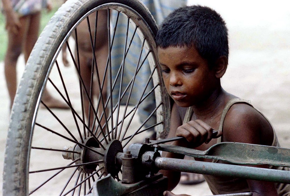 A child repairs the wheel of a tricycle rickshaw in the Bangladesh capital Dhaka September 6, 1996. u00e2u20acu201d Reuters pic