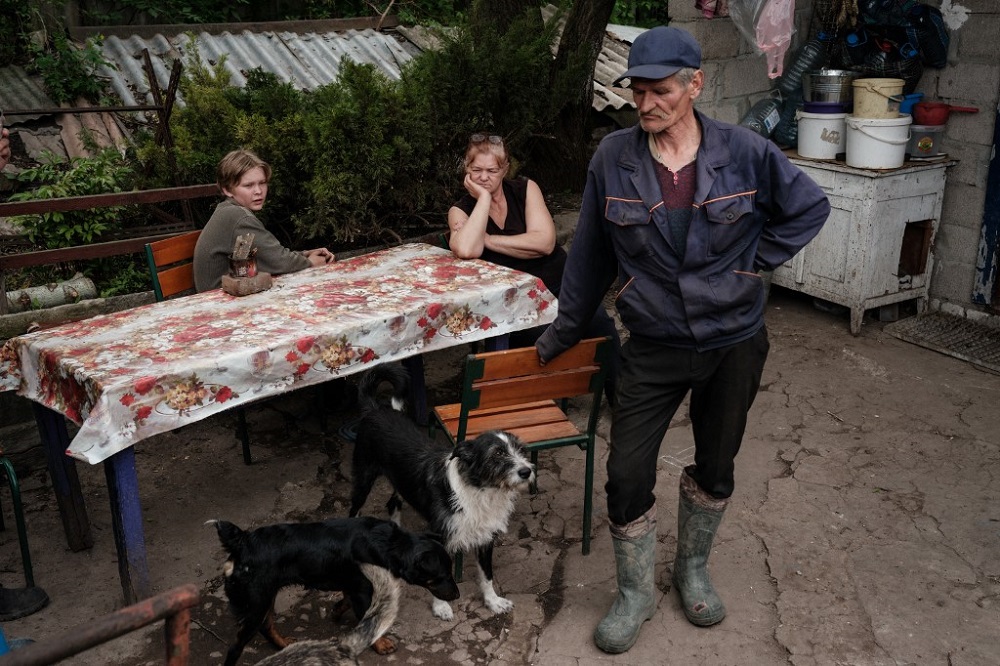 A family stands outside their home while living without electricity, water supply and phone network amid the Russian invasion of Ukraine, in Lysysyshansk May 15, 2022. — AFP pic
