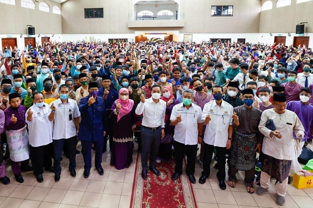 Johor Mentri Besar Datuk Onn Hafiz Ghazi doing the u00e2u20acu0153mini loveu00e2u20acu009d finger gesture and joined by teachers and students of Maktab Sultan Abu Bakar in conjunction with Teacheru00e2u20acu2122s Day celebration in Johor Baru May 16, 2022. u00e2u20acu201d Picture via Facebook/Onn Hafiz
