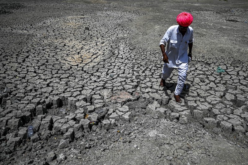 This photograph taken on May 11, 2022 shows Shivaram, a villager walking through the cracked bottom of a dried-out pond on a hot summer day at Bandai village in Pali district. u00e2u20acu201d AFP pic