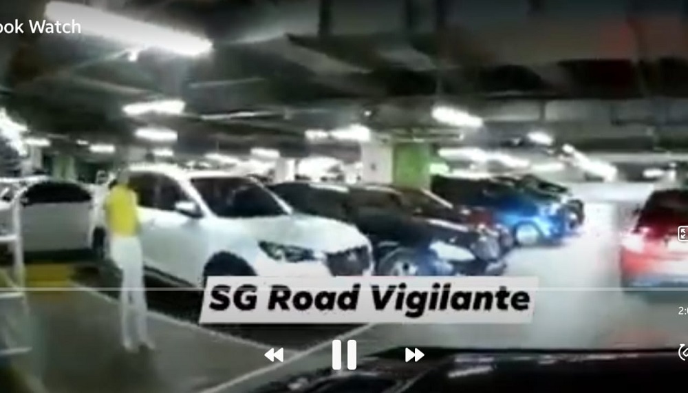 A woman in Singapore failed to reserve a parking lot for her husband after a driver reversed their vehicle into the lot the woman was standing on. u00e2u20acu201d Screen capture via  Facebook/ SG Road Vigilante