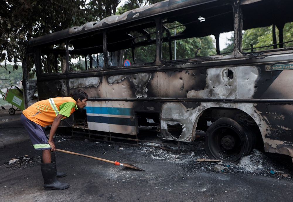 A man looks at a damaged bus of Sri Lanka's ruling party supporters after it was set on fire during a clash of pro and anti-government demonstrators near the prime minister's official residence, amid the country's economic crisis, in Colombo, Sri Lanka Ma