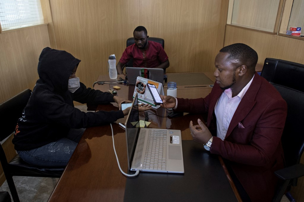 Ian James Mwai (right), 23, browses social media platforms on his mobile phone with a member of his outfit of social media influencers at an office in Thika town, central Kenya. u00e2u20acu201d AFP pic