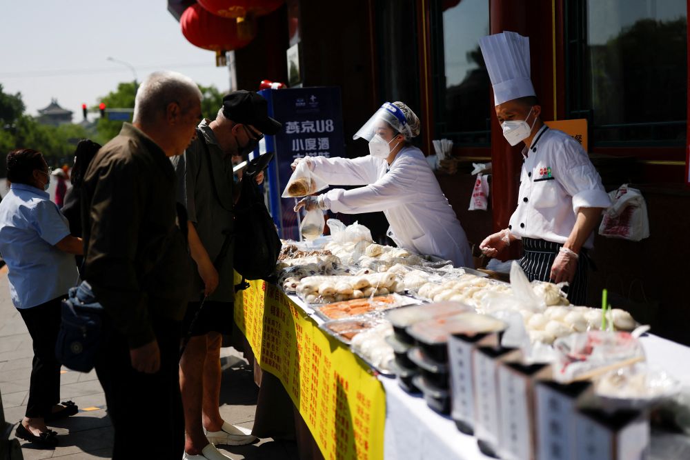 nWorkers wearing face masks sell food outside a restaurant, after the government banned dine-in services, following the Covid-19 outbreak in Beijing May 3, 2022. u00e2u20acu201d Reuters pic n